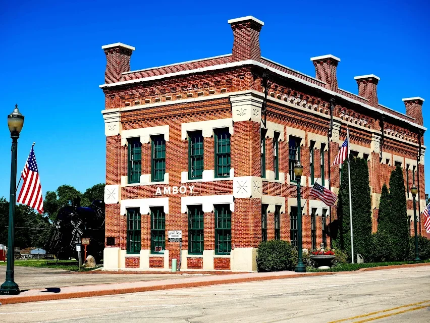 The real Amboy Depot Museum, a two-story red-brick Italianate depot with cream limestone and green windows, with a locomotive beside it